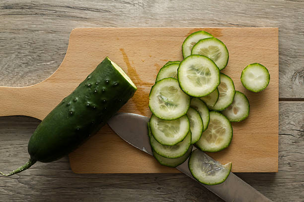 Sliced cucumber on wooden kitchen board Sliced cucumber on wooden kitchen board. Directly above view. Photo is taken with dslr camera in studio. cucumber slice stock pictures, royalty-free photos & images