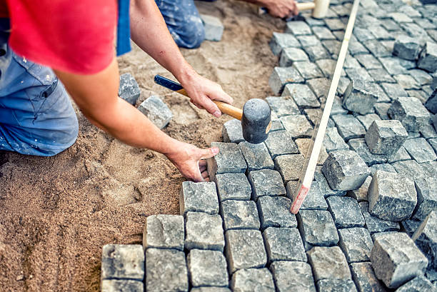 istock paving pavement with granite stones, workers using industrial cobblestones 501747976