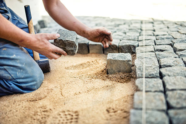 istock construction worker placing stone tiles in sand for pavement, terrace. 501748780
