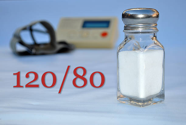 Blood Pressure, Salt, Hypertension, 120/80 A salt shaker with a blood pressure gauge in the background. Healthy blood pressure, 120/80. Combat hypertension with a healthy diet and low sodium. sodium intake stock pictures, royalty-free photos & images