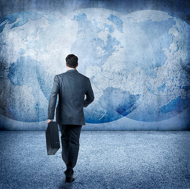 istock Businessman Walking Towrds Globes Projected On A Wall 501765306