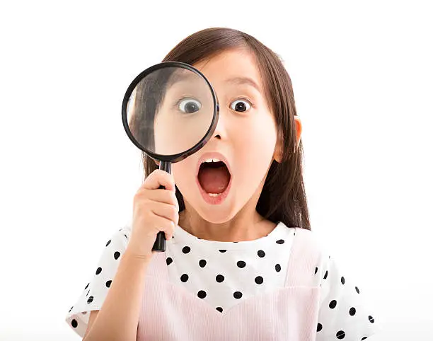 Photo of little girl looking through a magnifying glass