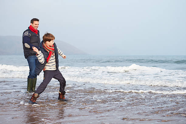 ojciec i syn spacery na plaży i rzucanie kamieniami zimowe - throwing stone little boys child zdjęcia i obrazy z banku zdjęć