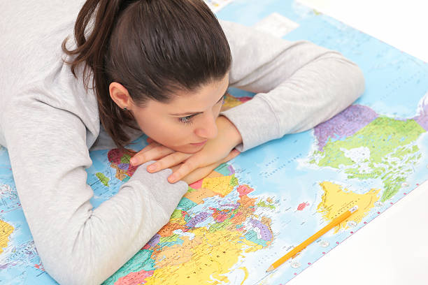 istock Young woman sitting on a map. 501776192
