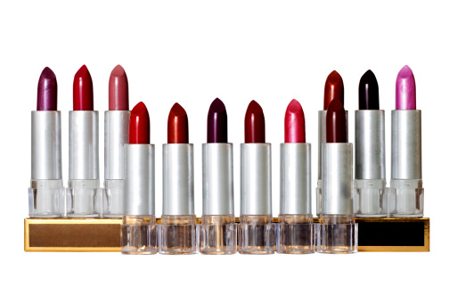 Multicolored Lipsticks, lined up in a row, before a white background (Clipped, isolated). The color palette includes Brown, Pink, Violet, Black, Purple and different flavours of red.