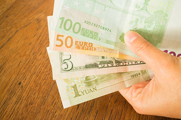 istock Hand on nternational currencies bank note on wooden table 501776292