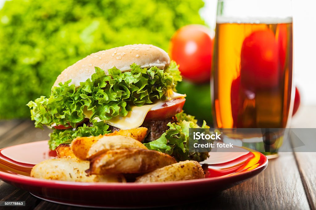 Hamburguesa con queso con papas fritas sobre una placa y cerveza - Foto de stock de Alimento libre de derechos