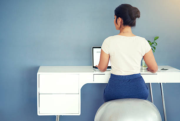 No tasks gets lefts behind Rearview shot of a young businesswoman working on her laptop at homehttp://195.154.178.81/DATA/i_collage/pi/shoots/806156.jpg fitness ball stock pictures, royalty-free photos & images