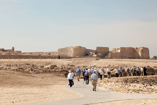 Manama, Bahrain - November 17, 2015: Group of tourists visiting the historic Fort of Bahrain. Kingdom of Bahrain, Middle East