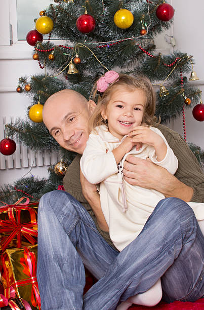 istock father and the little daughter under a New Year tree 501790258