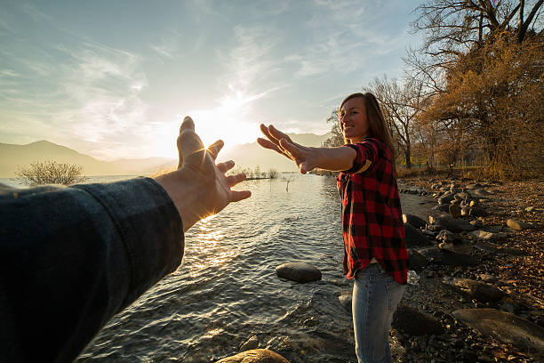 istock Young woman walks on lake shore holds a man's hand 501792692