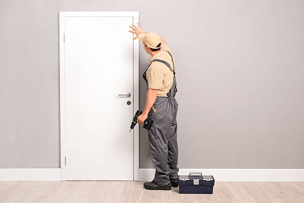 Young handyman installing a door Young handyman installing a white door with an electric hand drill in a room door repairman men manual worker stock pictures, royalty-free photos & images