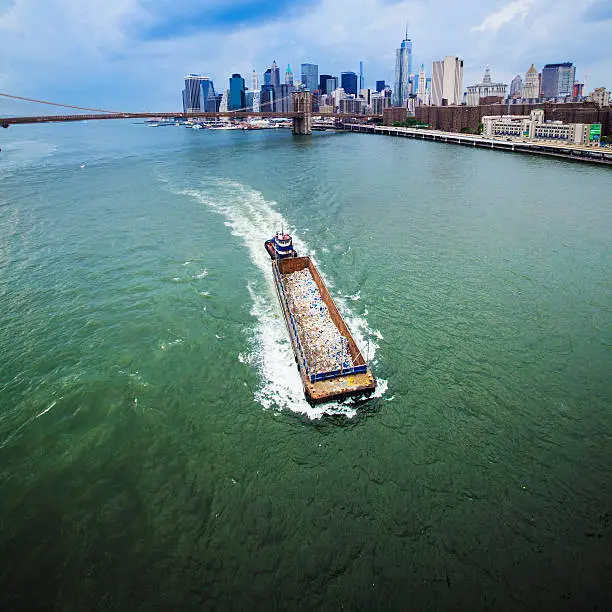 Barge with garbage at the East River between Brooklyn Bridge and Manhattan Bridge. New York City, USA. View from the Manhattan Bridge 