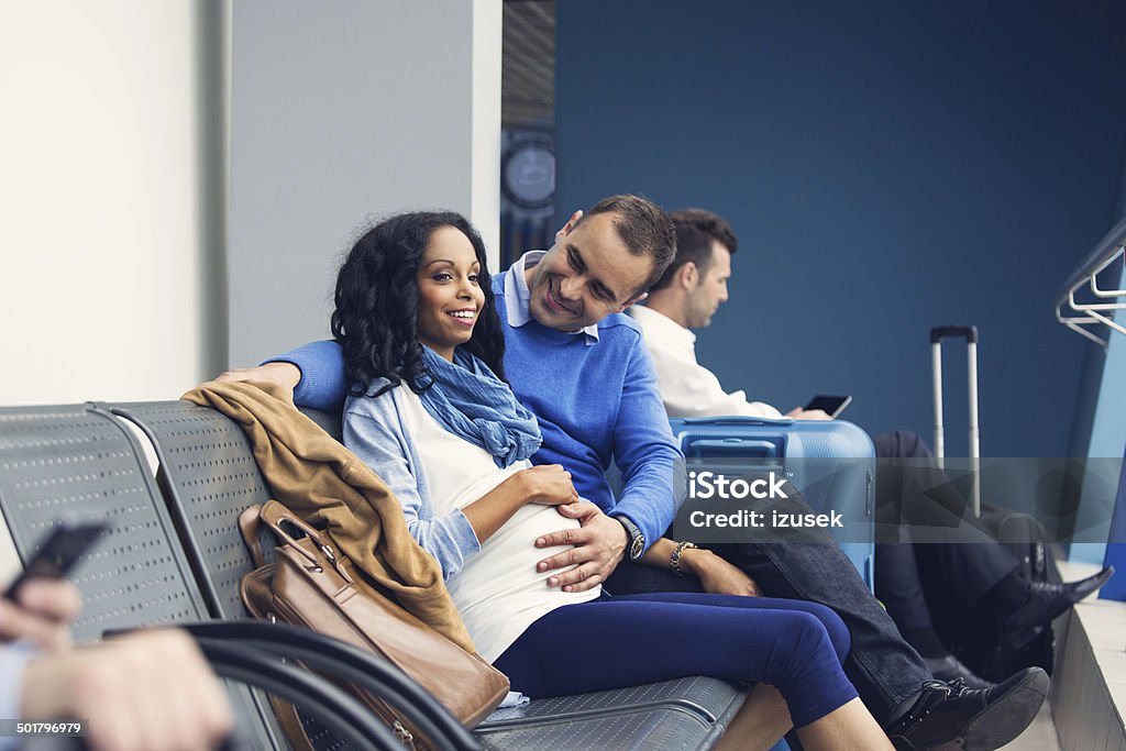 Couple waiting for flight Pregnant woman waiting with her partner for the flight at the airport lounge. Pregnant Stock Photo