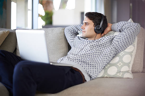Young woman with laptop and headphone on sofa