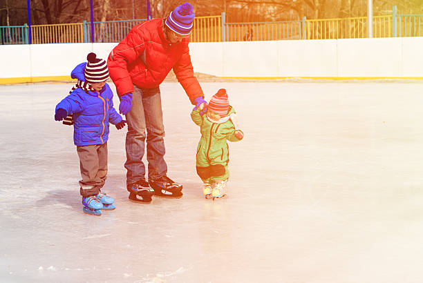 vater und zwei kinder eislaufen im winter - ice skating ice hockey child family stock-fotos und bilder