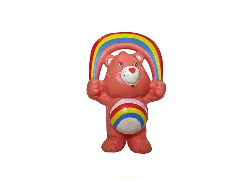 London, United Kingdom - June 19, 2014: Cheer Bear (one of the Care Bears) figurine. Care Bears were popular in the 1980s, they adorned greetings cards and then became popular in plush and figurine versions. They have different symbols on their tummies that symbolize their personalities - this one is 'cheer' bear. 