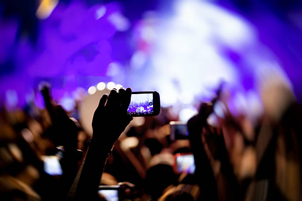 istock People taking photographs with touch smart phone during a music 501823350