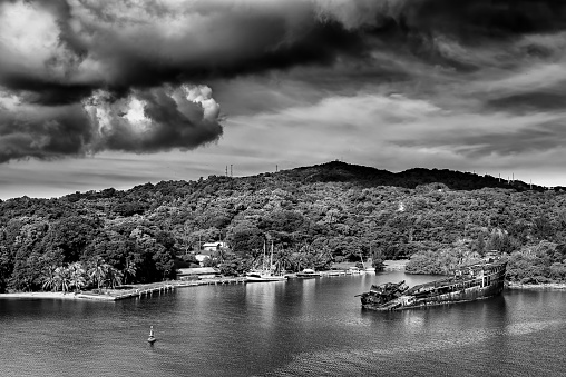Old whipwrecked vessel under an ominous sky off the coast of Roatan, Honduras