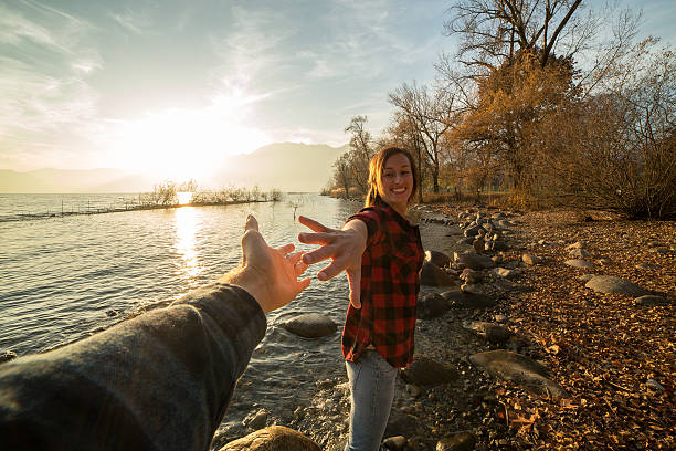 istock Young woman walks on lake shore holds a man's hand 501826200