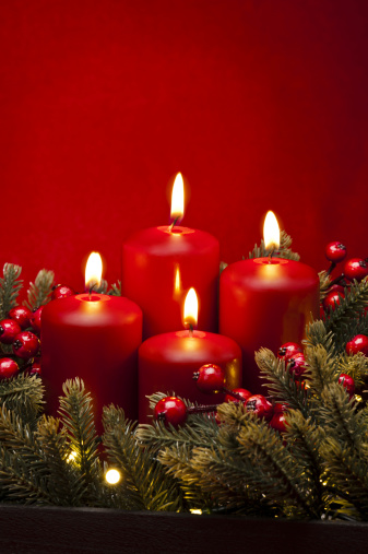 Red candle light Christmas candlelight on glowing flame sparkling green background blurred