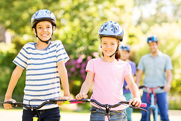 istock Smiling Siblings Wearing Cycling Helmets In Park 501832519