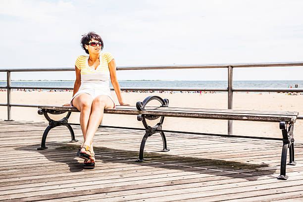 istock Young woman with apple sits at the bench at boardwalk 501832911