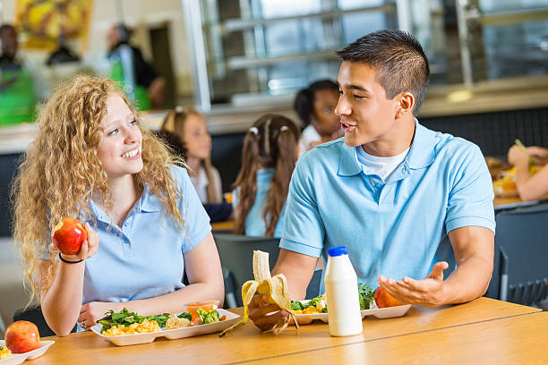 teen chłopiec i dziewczyna razem mając na obiad w szkolnej stołówce - apple eating healthy eating friendship zdjęcia i obrazy z banku zdjęć
