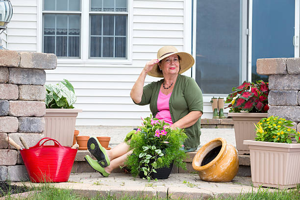 Elegant Grandma posing as she pots up plants on the steps of her home in terracotta pots to decorate the patio and house