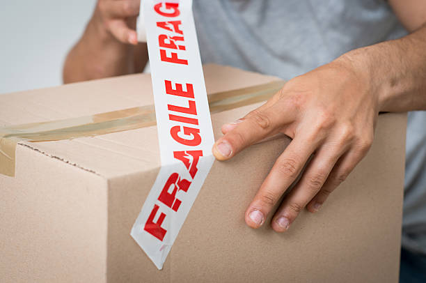 man sealing box with fragile adhesive - breekbaar stockfoto's en -beelden