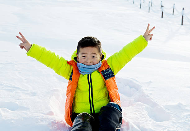 Young asian boy playing in the snow.