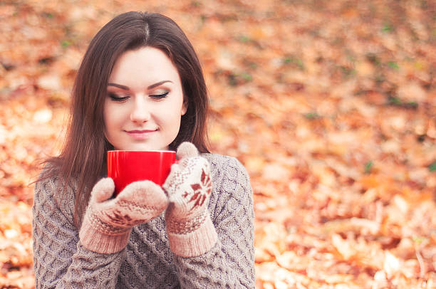 istock Young woman holding a big red cup and smelling tea 501850002