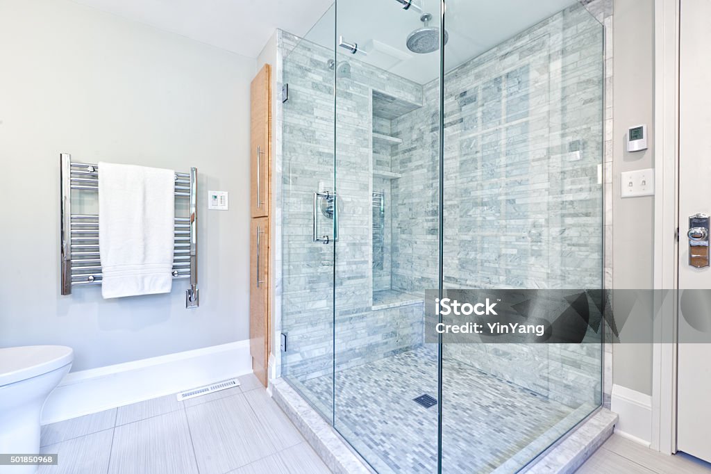 Contemporary Home Bathroom glass Shower Stall with Marble Tiles Contemporary interior bathroom design with glass enclosed shower stall with Cararra marble tiles. Duo shower heads with rain shower and conventional shower head. Heated towel rack hanger. Photographed in horizontal format. Shower Stock Photo
