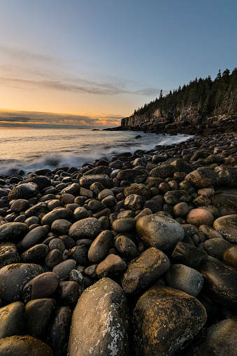 Sunrise image along rocky beach looking towards Otter Cliff in Acadia National Park, Maine.  