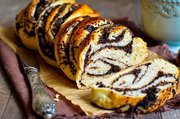 Yeast roll with poppy seed on rustic background.