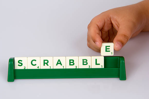 Konak,İzmir,Turkey- June 15, 2014: A kid's hand putting Scrabble letter tile on the board and Scrabble distributed by Mattel.