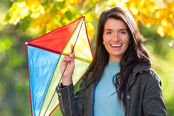 Young woman outdoors in autumn, flying kite.