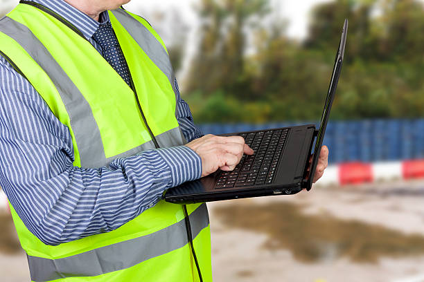 istock Building surveyor in hi vis vest using his laptop 501878858