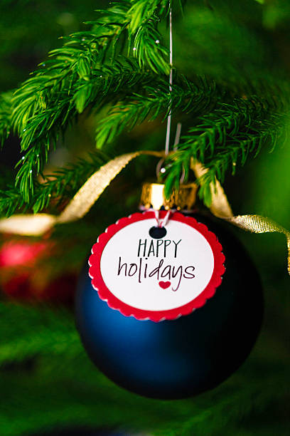 istock Christmas bauble with Happy Holidays message on Christmas tree branches 501886336