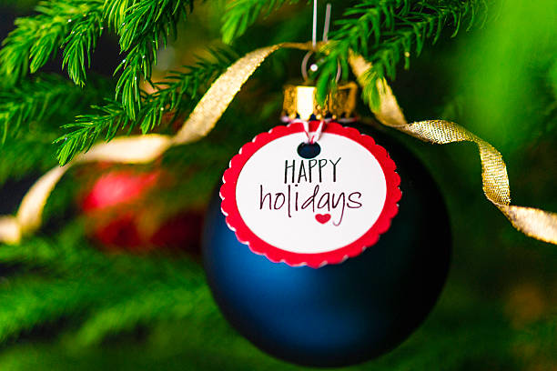 Christmas bauble with Happy Holidays message on Christmas tree branches