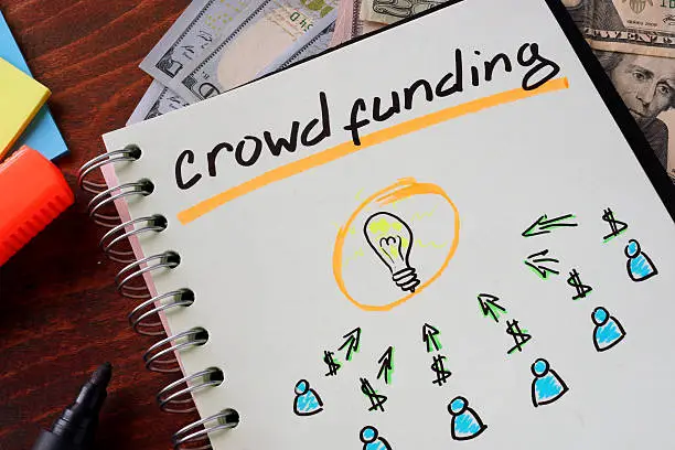 Photo of Notebook with crowd funding sign on a table.