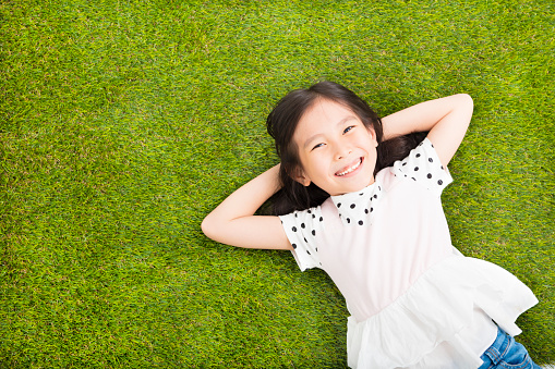 happy Little  girl resting on the grass