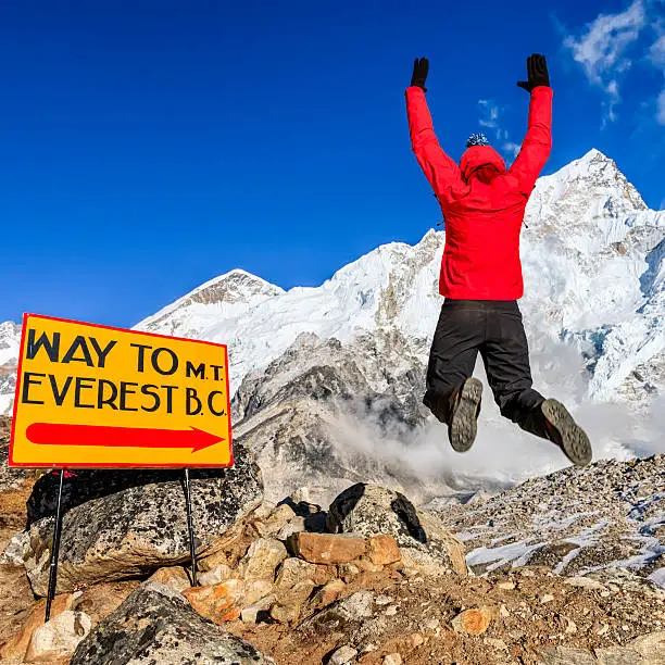 Young woman, wearing red jacket, is jumping next to the signpost "Way to Mount Everest Base Camp" in Mount Everest National Park. This is the highest national park in the world, with the entire park located above 3,000 m ( 9,700 ft). This park includes three peaks higher than 8,000 m, including Mt Everest. Therefore, most of the park area is very rugged and steep, with its terrain cut by deep rivers and glaciers. Unlike other parks in the plain areas, this park can be divided into four climate zones because of the rising altitude.http://bhphoto.pl/IS/nepal_380.jpg