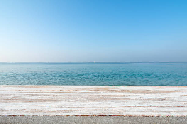 istock Wood table top on blurred blue sea and white 501905326