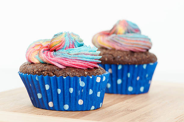 Two Chocolate cupcake with rainbow icing and a yellow candle stock photo