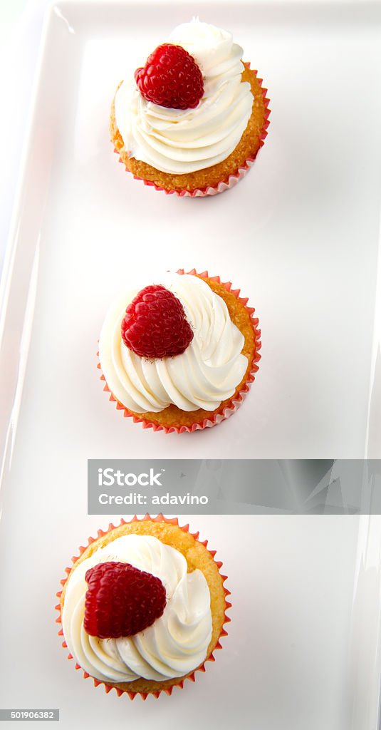 Vanilla Cupcakes with cream and a red berry on top Three Vanilla Cupcakes with white whipped cream and a red cherry on top, placed on a white plate isolated on a white background Vanilla Cupcakes with white whipped cream and a red cherry on top, placed on a white plate isolated on a white background Vanilla Cupcakes with white whipped cream and a red cherry berry on top, placed on a white plate isolated on a white background Cupcake Stock Photo