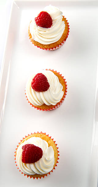 Vanilla Cupcakes with cream and a red berry on top stock photo