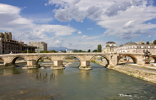 Skopje, Macedonia - September 6, 2015: The Stone Bridge Over Vardar River in Skopje, Macedonia. The Stone Bridge is a bridge across the Vardar River in Skopje, the capital of the Republic of Macedonia. The bridge is considered a symbol of Skopje and is the main element of the coat of arms of the city, which in turn is incorporated in the city's flag. The Stone Bridge connects Macedonia Square, in the center of Skopje, to the Old Bazaar. The bridge is also less frequently known as the Dušan Bridge after Stephen Uroš IV Dušan of Serbia.