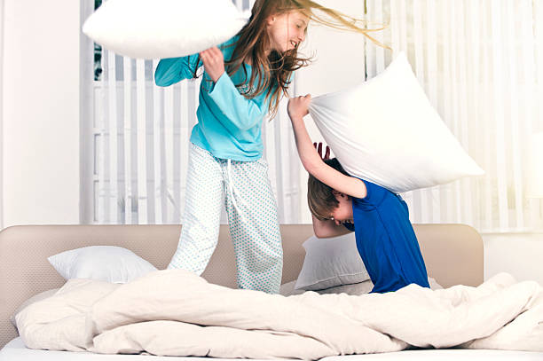 los niños de padres playfighting cama - lucha con almohada fotografías e imágenes de stock