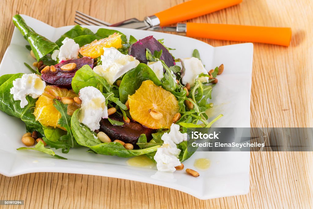 fresh salad with roasted beetroot, white cheese, orange and pine fresh salad with roasted beetroot, white cheese, orange and pine nuts with orange fork and knife 2015 Stock Photo
